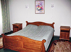 В спальне располагается широкая двуспальная кровать с прикроватными тумбочками